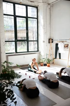 a group of people sitting on top of yoga mats in a room next to a window