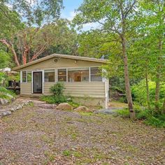 a small house in the woods with trees around it and rocks on the ground next to it