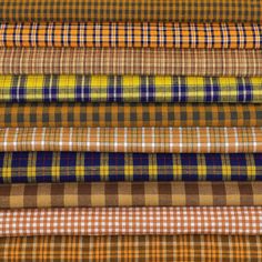 a stack of different colored plaid fabric on top of each other in various sizes and colors