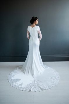 a woman in a white wedding dress is standing on the floor with her hands on her hips