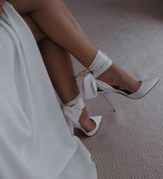 a woman wearing white high heels sitting on top of a bed