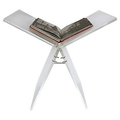 an open book sitting on top of a metal stand with two books in the middle