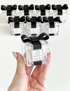 a hand holding a small clear box with black ribbon