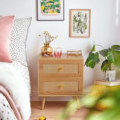 a bed room with a neatly made bed next to a plant and pictures on the wall