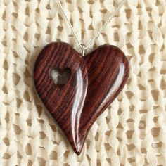 a wooden heart necklace with a hole in the middle