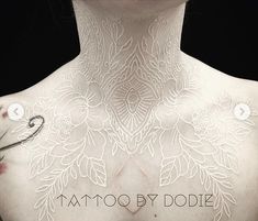 the back of a woman's body with tattoos on her chest and words written across it