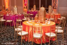 an elaborately decorated banquet room with orange and pink linens