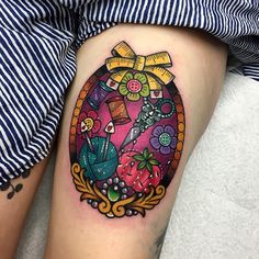 a woman's leg with a colorful tattoo on it and an oval frame in the middle