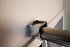 a close up of a metal handle on a white wall with a black and silver door