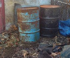 three metal barrels sitting next to each other on the ground