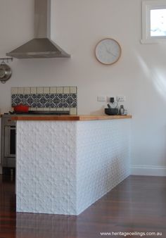 a kitchen with a stove top oven and counter tops next to a wall mounted clock