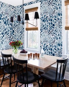 a dining room table with four chairs and a vase on the table in front of it