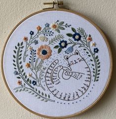 the embroidery is hanging on the wall with flowers and leaves in it's hoop