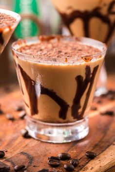 two desserts are sitting on a table with chocolate sauce and coffee beans around them