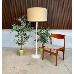 a chair next to a table with a lamp on it and a potted plant