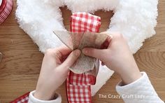 a person is holding a piece of fabric near a teddy bear's head and ribbon