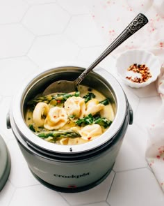 a pot filled with pasta and broccoli on top of a white tiled counter