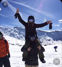 a man is holding two children on his shoulders in the snow