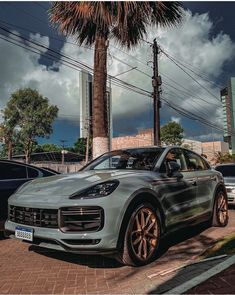 a porsche cayen is parked on the side of the road in front of some palm trees