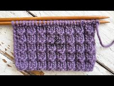 a purple knitted object with two knitting needles next to it