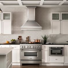 a stove top oven sitting inside of a kitchen next to white cabinets and counter tops