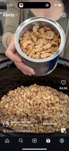 someone is holding a can of peanuts over the top of an open tinned container