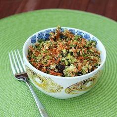 a bowl filled with food sitting on top of a green place mat next to a fork