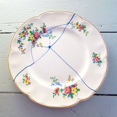 a white plate with flowers on it sitting on top of a wooden table next to a wall