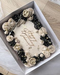 a birthday cake in a white box with black and gold decorations on the edges that says happy birthday