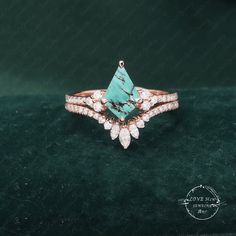 a turquoise stone and diamond ring on top of a green velvet surface