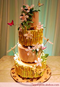 a three tiered cake decorated with bamboo and flowers