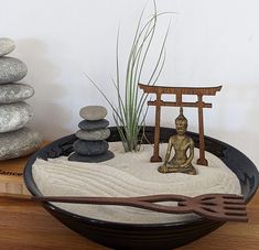 a bowl that has some rocks in it and a statue sitting on top of it