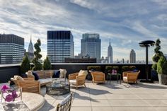 an outdoor seating area on top of a building with city skyline in the background,