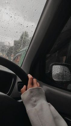 a person is driving in the rain with their hand on the steering wheel