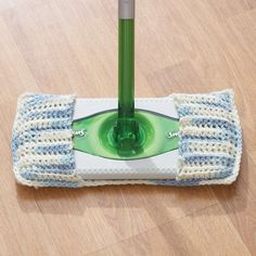 a green and white mop sitting on top of a wooden floor