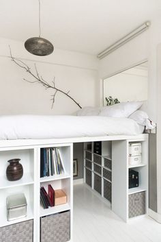 there is a bed with white sheets and bookshelves in the room, next to an open bookcase