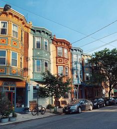 a row of multi - colored buildings on the corner of a street with parked cars