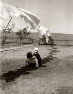 two children sitting on the ground with an umbrella in front of them and one child looking up at it