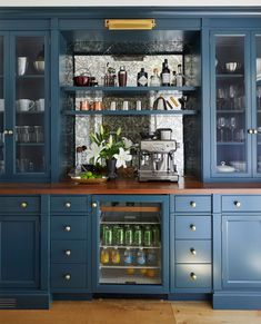 a kitchen with blue cabinets and shelves filled with bottles, glasses, and other items