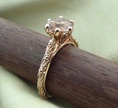 a close up of a gold ring on a wooden stick with a green cloth in the background