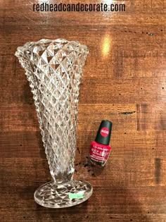 a glass vase sitting on top of a wooden table next to a bottle of deodorant