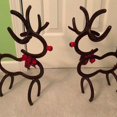 two metal deer sculptures sitting on top of a carpeted floor next to a door