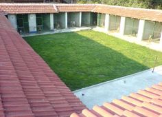 an aerial view of a courtyard and lawn from the roof of a building with red tiled roofs