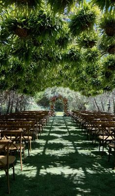 an outdoor ceremony setup with rows of chairs and tables set up in the shade under trees