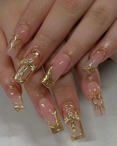 a woman's nails with gold decorations on them and some nail polish in the middle