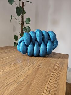 a pile of blue balls sitting on top of a wooden table next to a potted plant