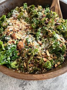 a wooden bowl filled with broccoli covered in nuts and parmesan cheese