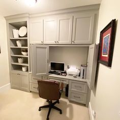 a home office with built in cabinets and desk