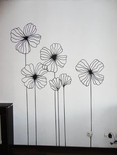 three metal flowers on a white wall next to a black and white dresser with drawers