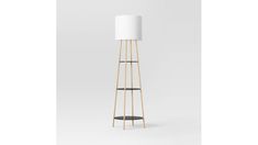 a tall wooden floor lamp with a white shade on it's top and two black shelves below